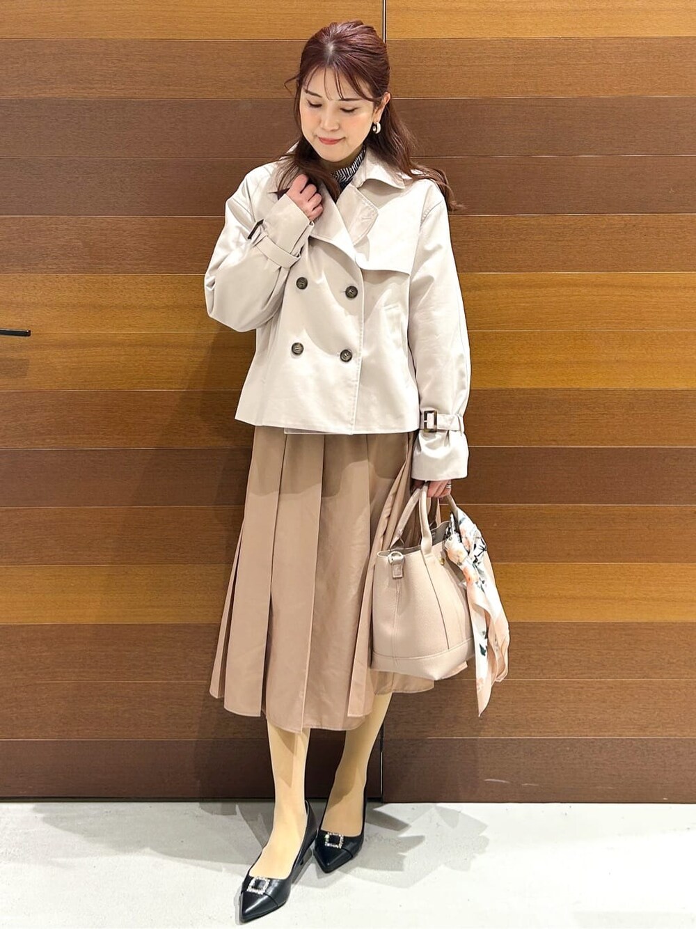 ベージュ系のトレンチコート、ブルー系のシャツ/ブラウス、ベージュ系のスカートを着用したレディースの春コーディネートの3枚目の写真