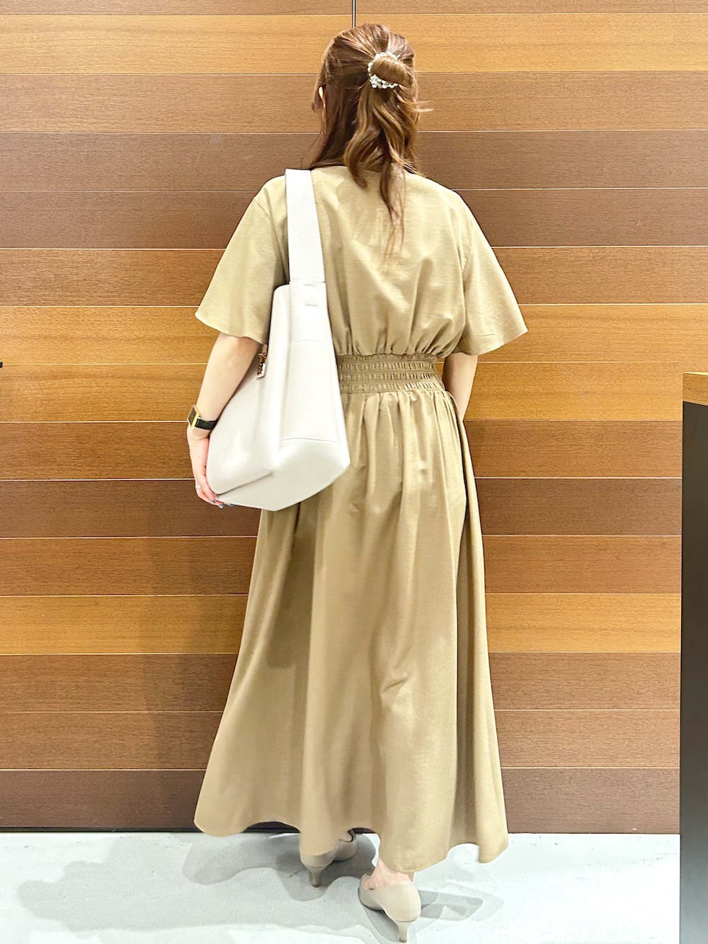 イエロー系のワンピース、グレー系のトートバッグ、ベージュ系のパンプスを着用したレディースの夏コーディネートの5枚目の写真