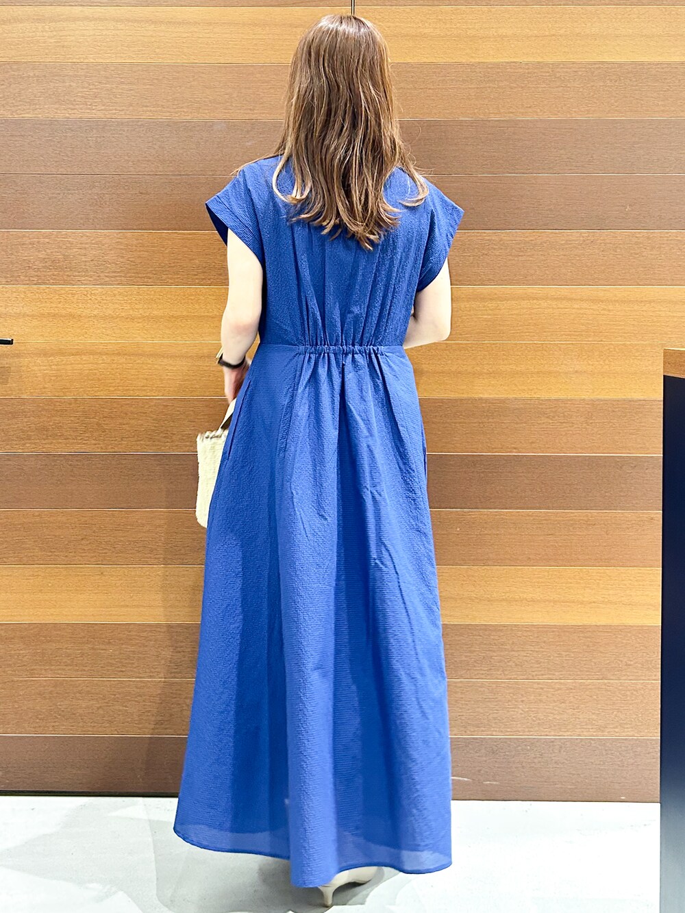 ブルー系のワンピース、ベージュ系のトートバッグ、ベージュ系のパンプスを着用したレディースの夏コーディネートの6枚目の写真