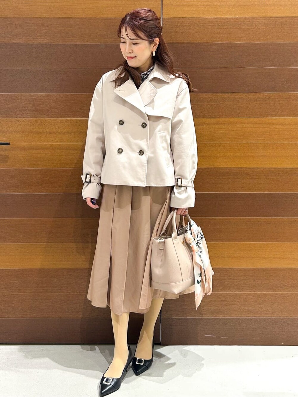 ベージュ系のトレンチコート、ブルー系のシャツ/ブラウス、ベージュ系のスカートを着用したレディースの春コーディネートの2枚目の写真