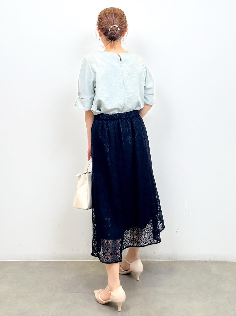 グリーン系のシャツ/ブラウス、ブルー系のスカート、ホワイト系のショルダーバッグを着用したレディースの夏コーディネートの3枚目の写真