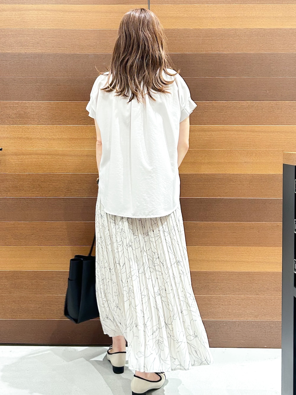 ベージュ系のシャツ/ブラウス、ブラック系のトートバッグ、ベージュ系のパンプスを着用したレディースの夏コーディネートの4枚目の写真