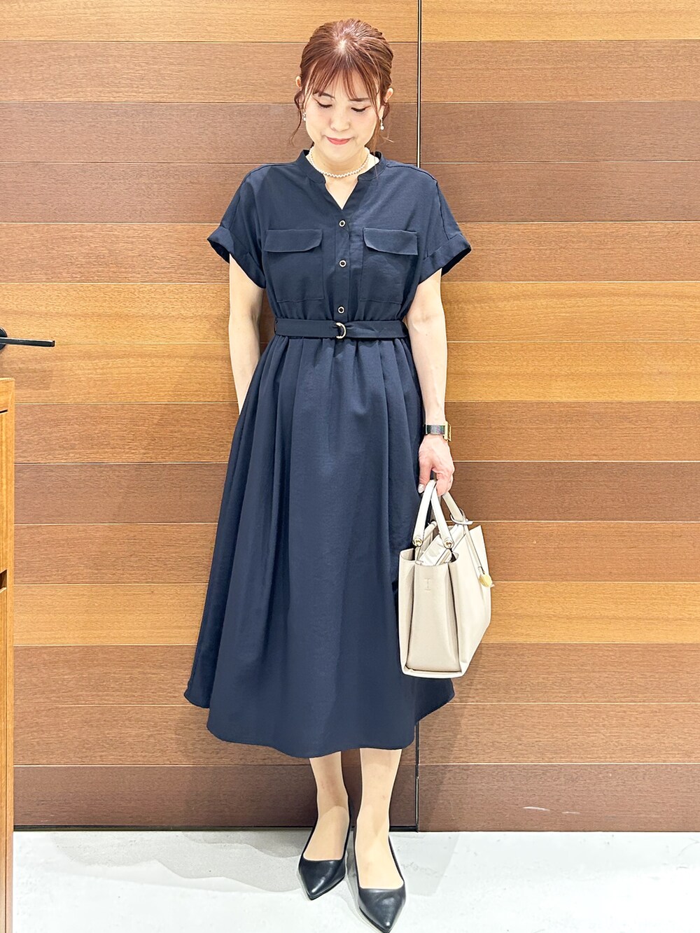 ブルー系のワンピース、ベージュ系のトートバッグ、ブラック系のパンプスを着用したレディースの夏コーディネートの2枚目の写真