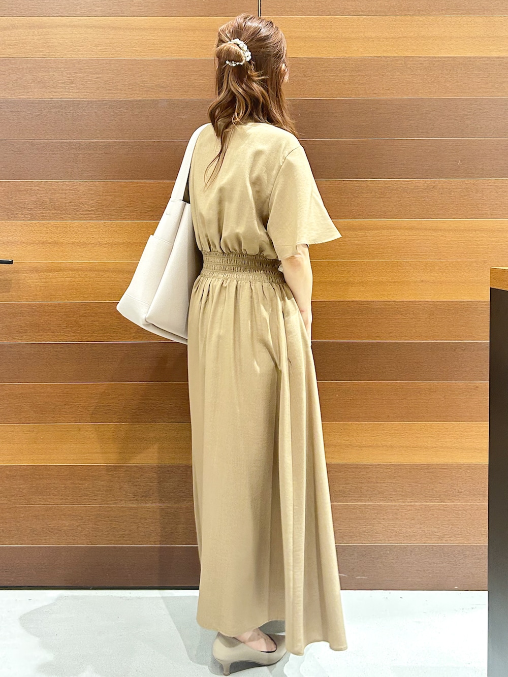 イエロー系のワンピース、グレー系のトートバッグ、ベージュ系のパンプスを着用したレディースの夏コーディネートの6枚目の写真
