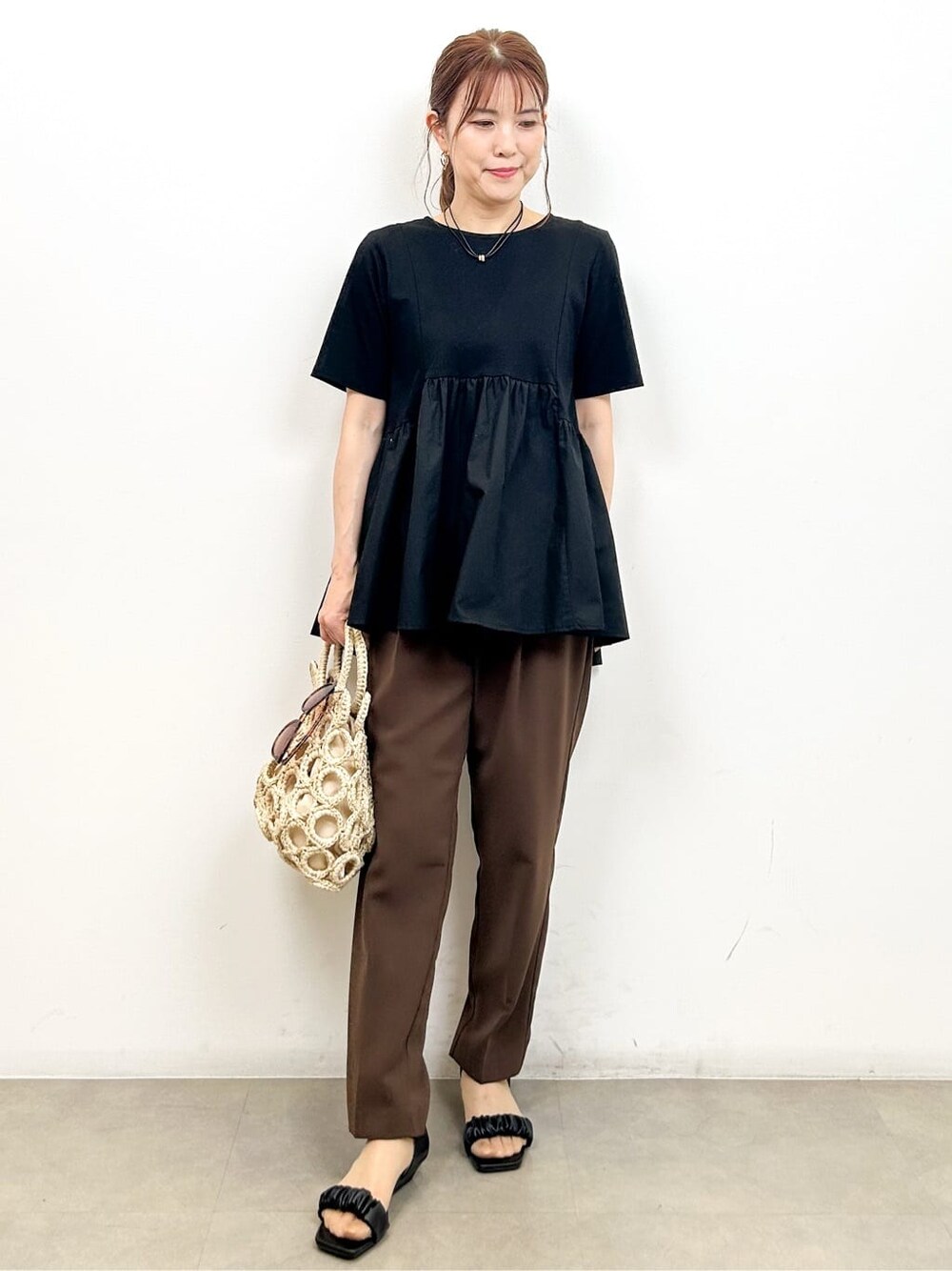 ブラック系のTシャツ/カットソー、ブラウン系のその他パンツ、ホワイト系のハンドバッグを着用したレディースの夏コーディネートの4枚目の写真