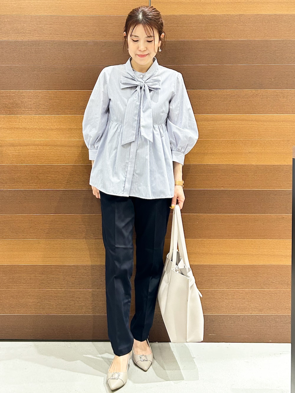 ベージュ系のパンプス、ブルー系のシャツ/ブラウス、グレー系のトートバッグを着用したレディースの春コーディネートの2枚目の写真