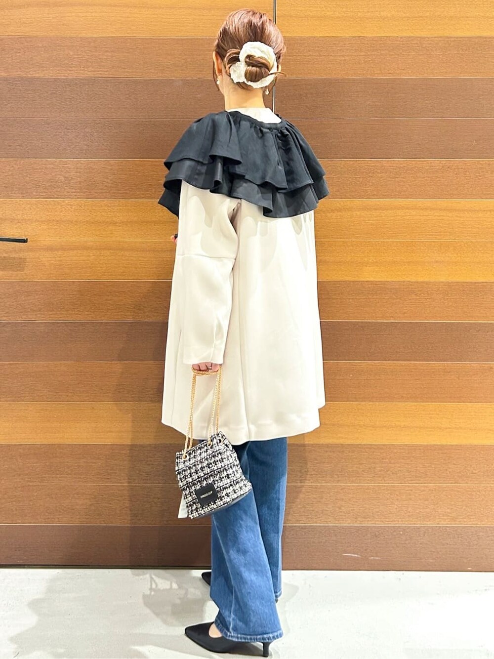 ブルー系のデニムパンツ、ホワイト系のノーカラーコート、ブラック系のショルダーバッグを着用したレディースの春コーディネートの5枚目の写真