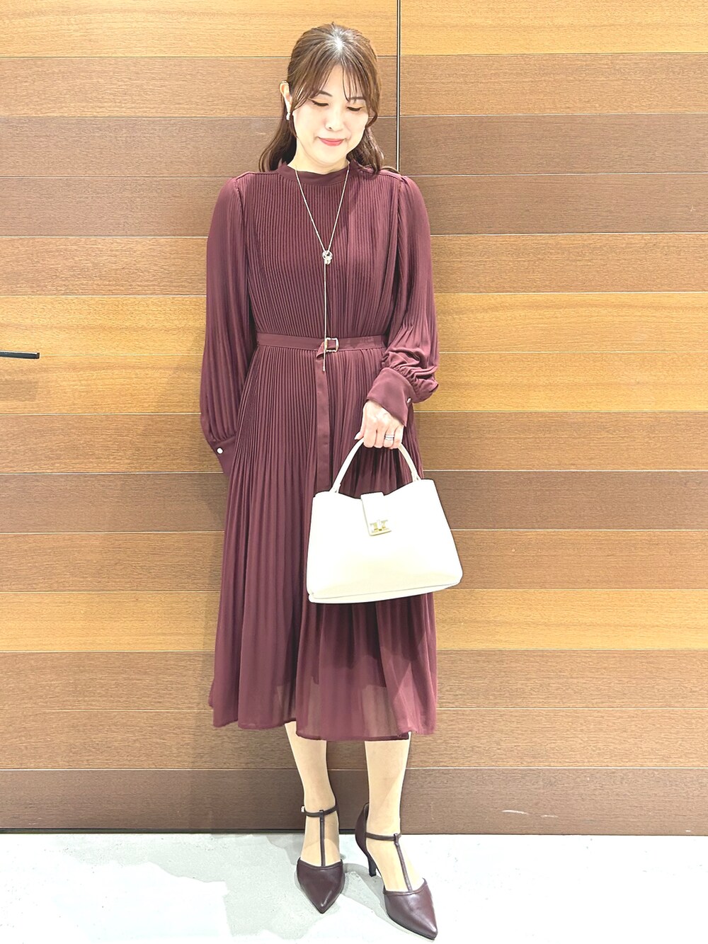 レッド系のワンピース、ホワイト系のハンドバッグ、レッド系のパンプスを着用したレディースの秋コーディネートの3枚目の写真
