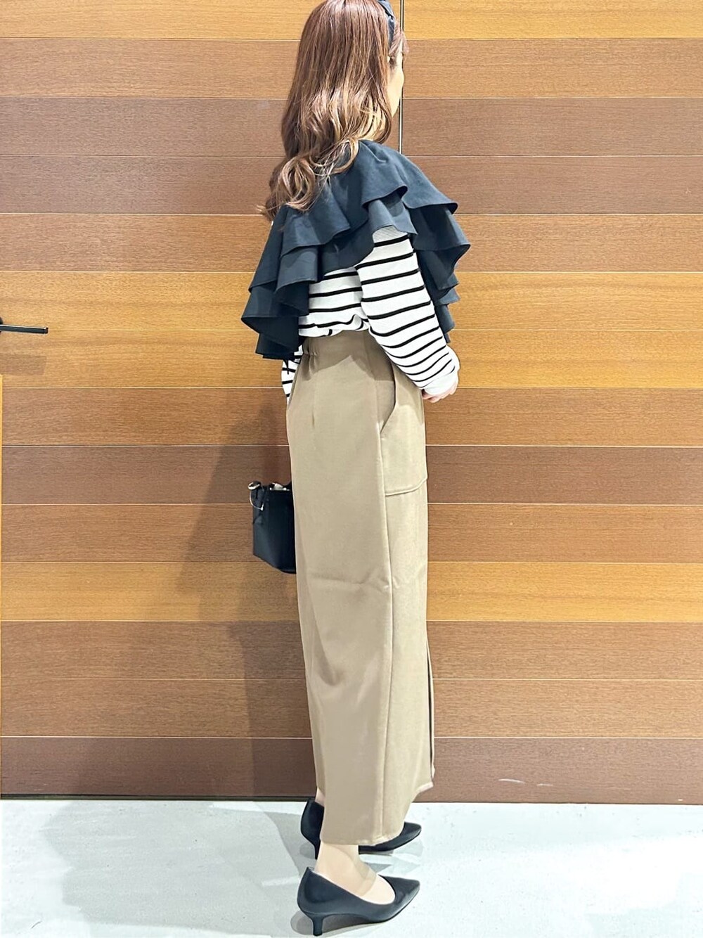 ブラック系のパンプス、ベージュ系のショルダーバッグ、ブラウン系のスカートを着用したレディースの春コーディネートの8枚目の写真