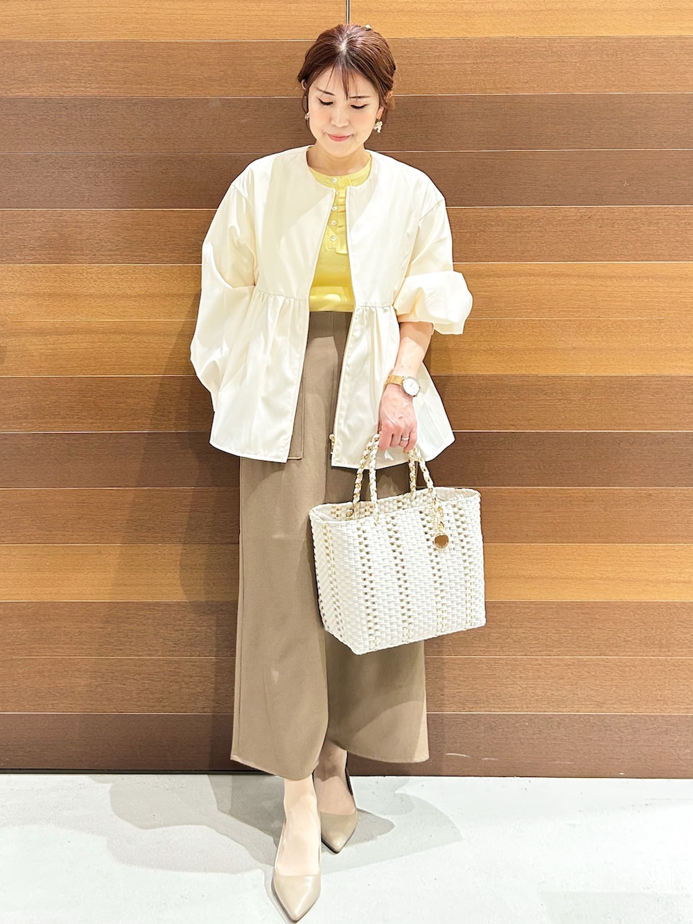 ベージュ系のパンプス、ベージュ系のショルダーバッグ、ブラウン系のスカートを着用したレディースの春コーディネートの7枚目の写真