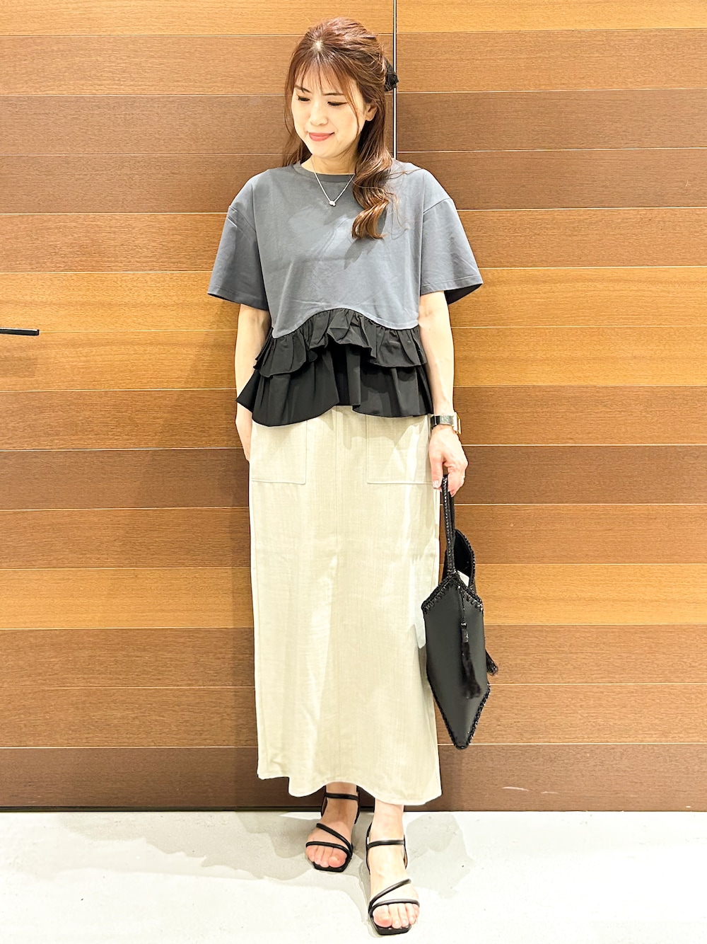 グレー系のTシャツ/カットソー、ベージュ系のスカート、ブラック系のハンドバッグを着用したレディースの夏コーディネートの2枚目の写真