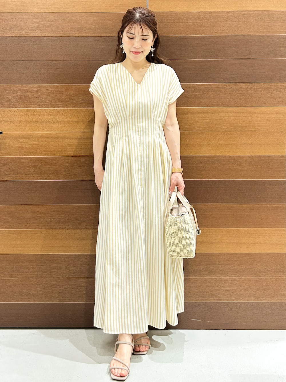 ベージュ系のトートバッグ、ベージュ系のサンダル、ベージュ系のワンピースを着用したレディースの春コーディネートの2枚目の写真