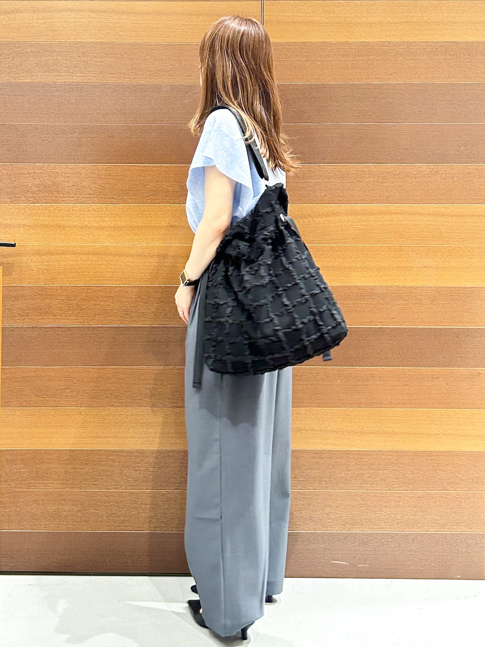 ブルー系のニット/セーター、グレー系のその他パンツ、ブラック系のトートバッグを着用したレディースの夏コーディネートの4枚目の写真