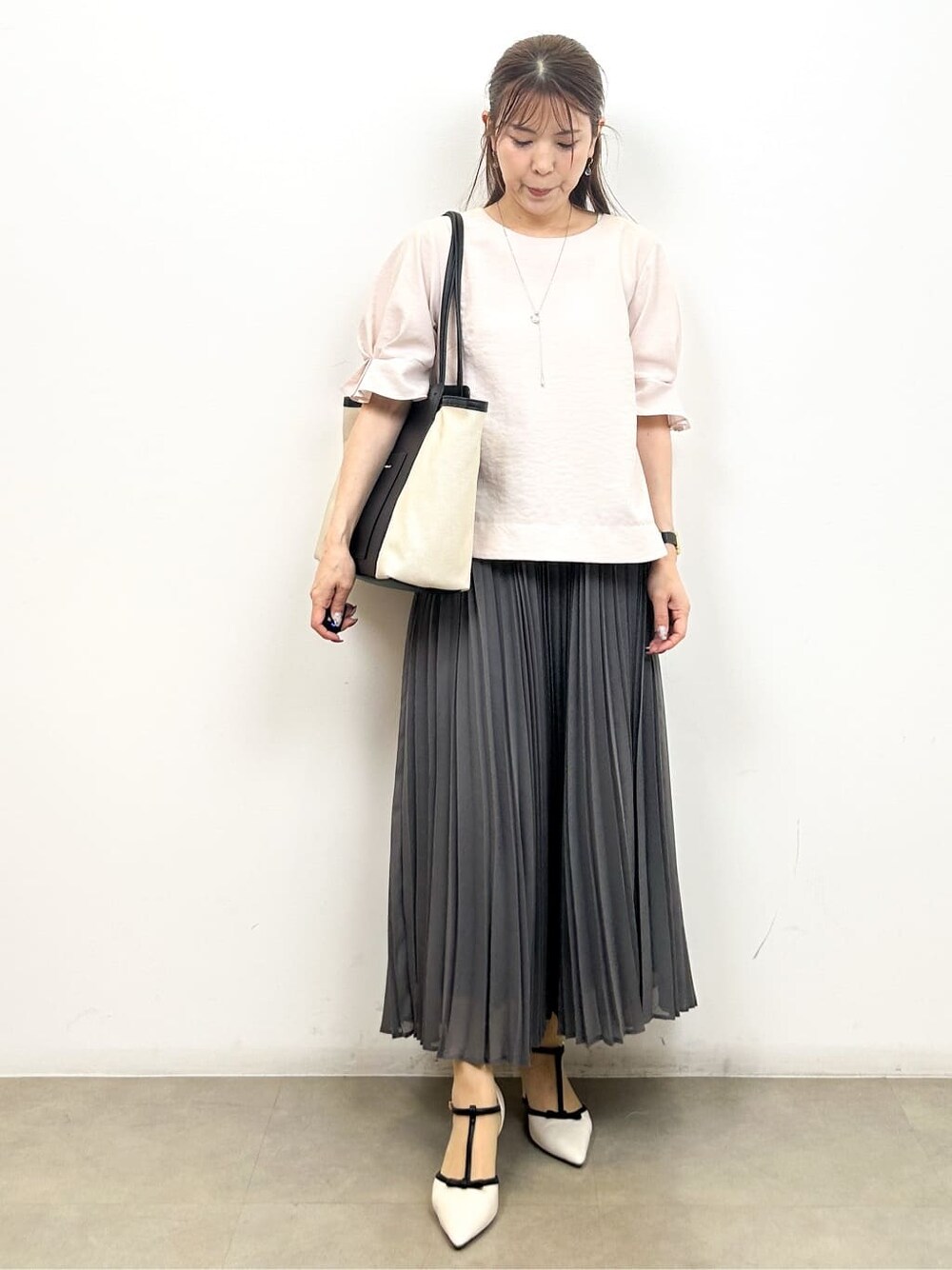 ピンク系のシャツ/ブラウス、ブラック系のトートバッグ、ホワイト系のパンプスを着用したレディースの夏コーディネートの7枚目の写真