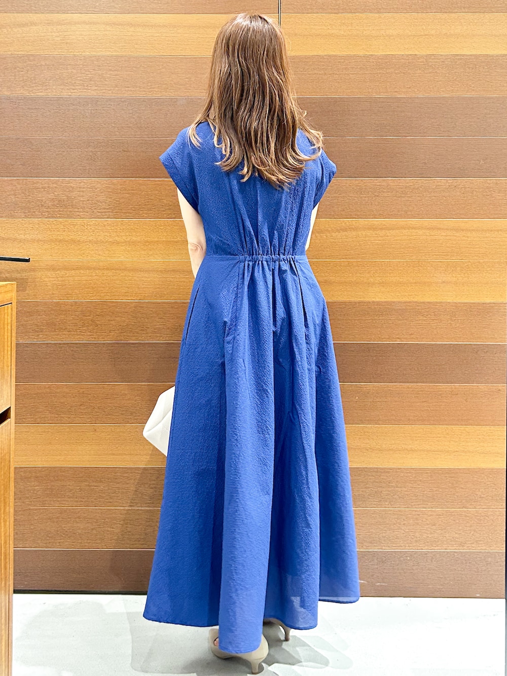 ブルー系のワンピース、グレー系のトートバッグ、ベージュ系のパンプスを着用したレディースの夏コーディネートの6枚目の写真