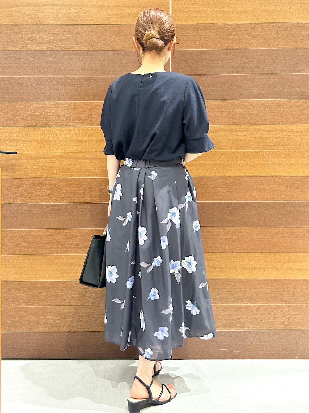 ブルー系のシャツ/ブラウス、グレー系のスカート、ブラック系のトートバッグを着用したレディースの夏コーディネートの5枚目の写真