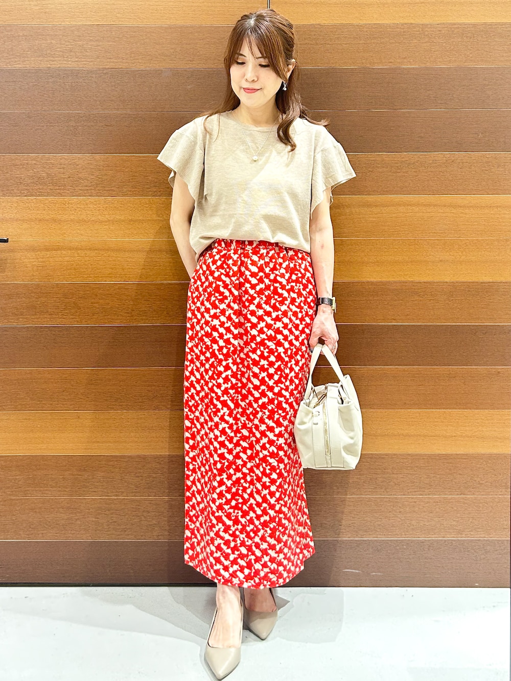ベージュ系のニット/セーター、レッド系のスカート、グレー系のボストンバッグを着用したレディースの夏コーディネートの2枚目の写真