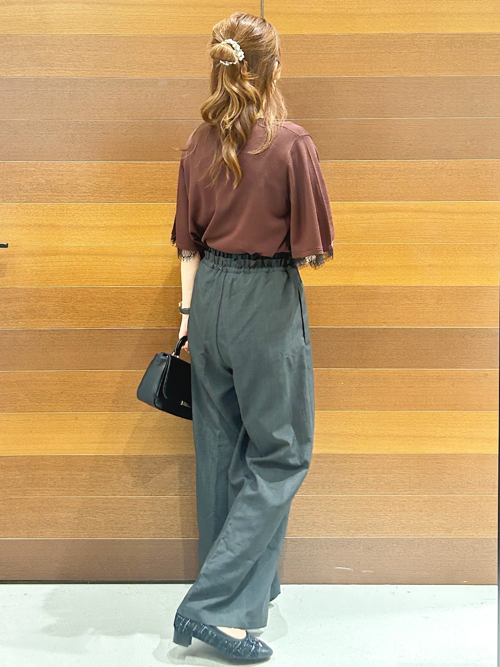 ブラウン系のニット/セーター、グレー系のその他パンツ、ブラック系のショルダーバッグを着用したレディースの夏コーディネートの6枚目の写真