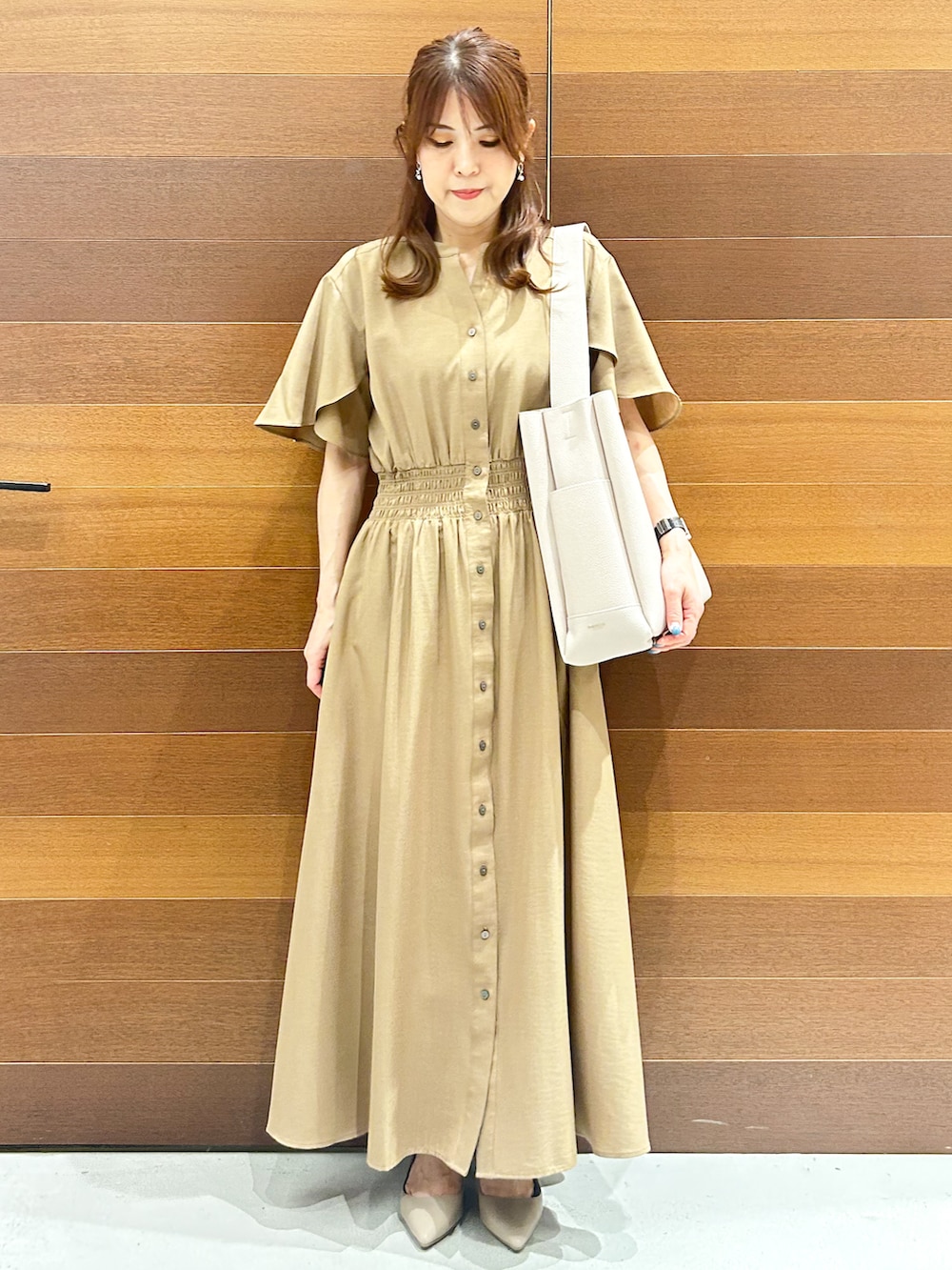 イエロー系のワンピース、グレー系のトートバッグ、ベージュ系のパンプスを着用したレディースの夏コーディネートの4枚目の写真