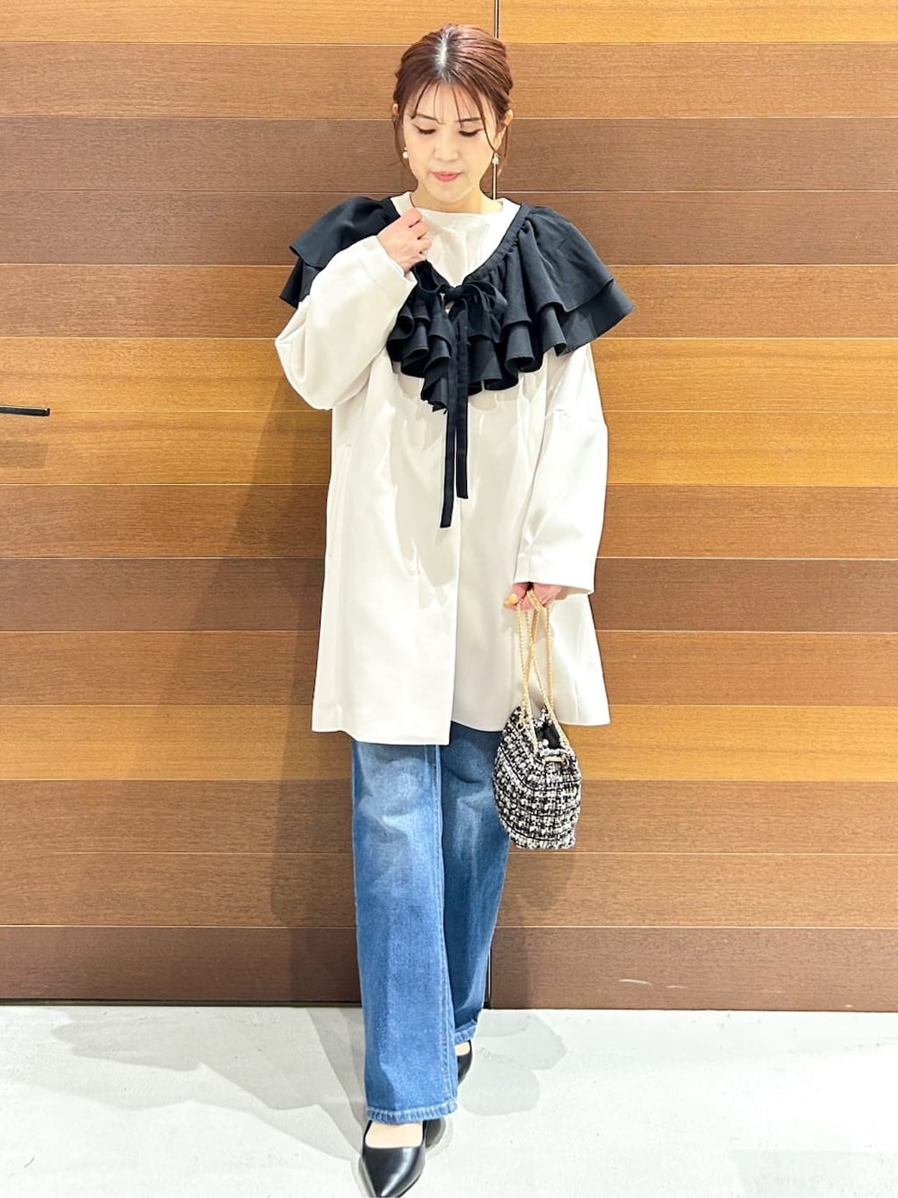 ブルー系のデニムパンツ、ホワイト系のノーカラーコート、ブラック系のショルダーバッグを着用したレディースの春コーディネートの3枚目の写真