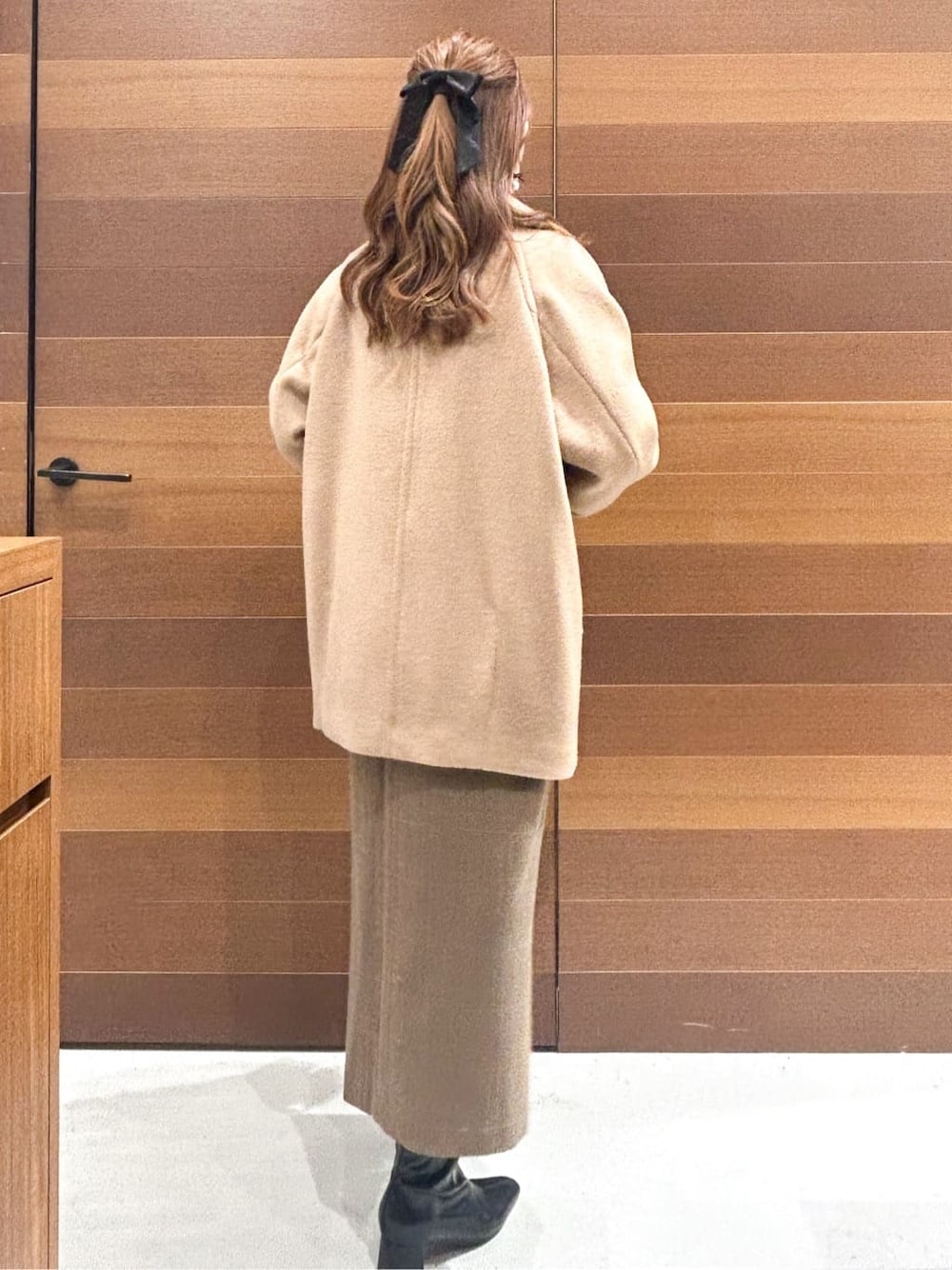 ベージュ系のピーコート、レッド系のニット/セーター、ブラウン系のワンピースを着用したレディースの冬コーディネートの10枚目の写真