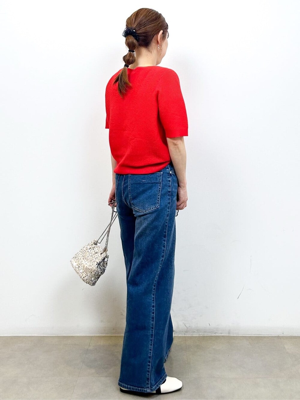 レッド系のカーディガン/ボレロ、ブルー系のデニムパンツ、ホワイト系のショルダーバッグを着用したレディースの夏コーディネートの6枚目の写真