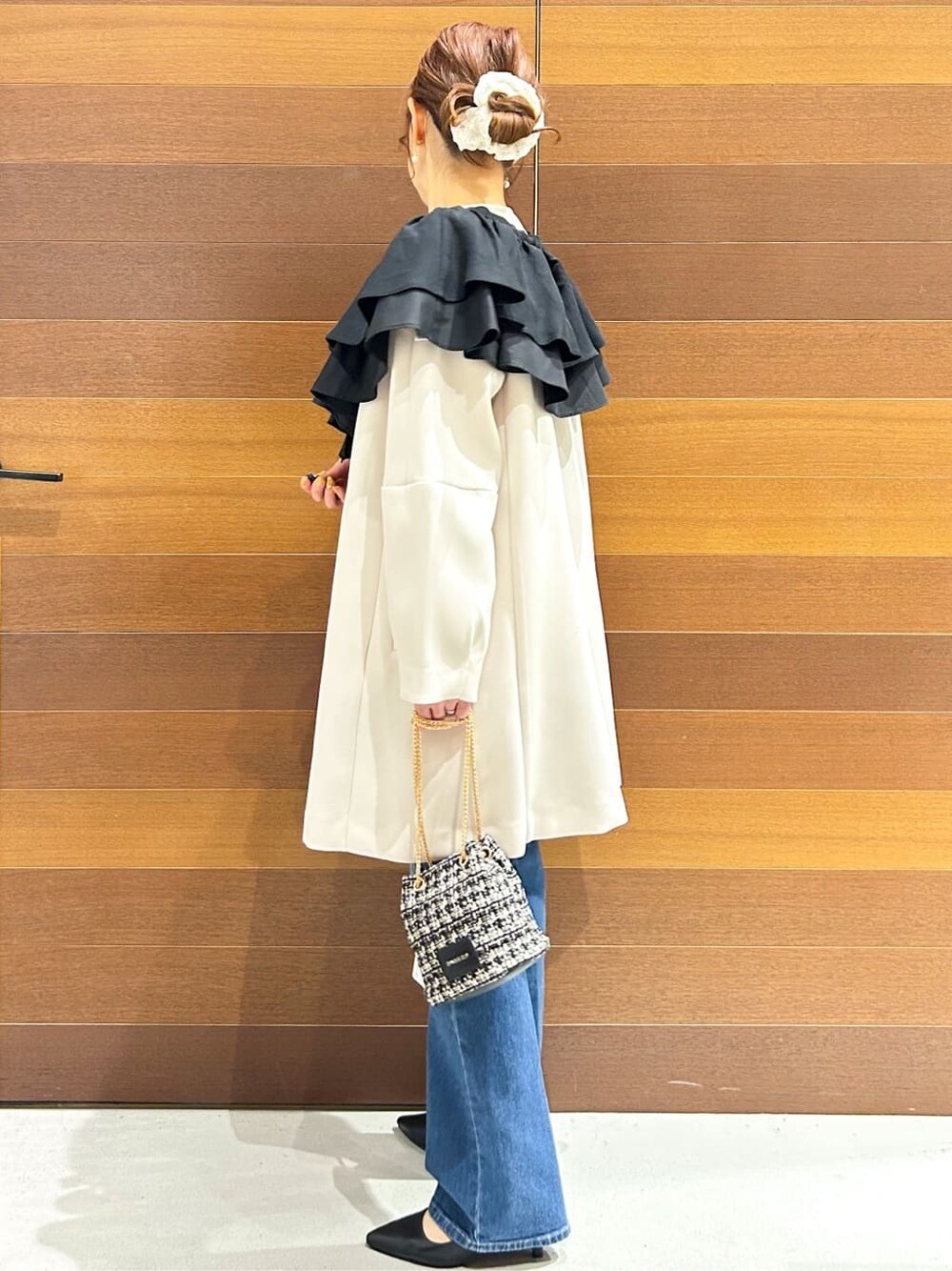ブルー系のデニムパンツ、ホワイト系のノーカラーコート、ブラック系のショルダーバッグを着用したレディースの春コーディネートの4枚目の写真