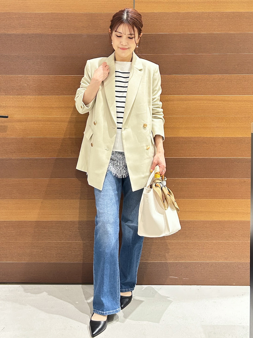 ブルー系のデニムパンツ、ホワイト系のショルダーバッグ、ブラック系のパンプスを着用したレディースの春コーディネートの2枚目の写真
