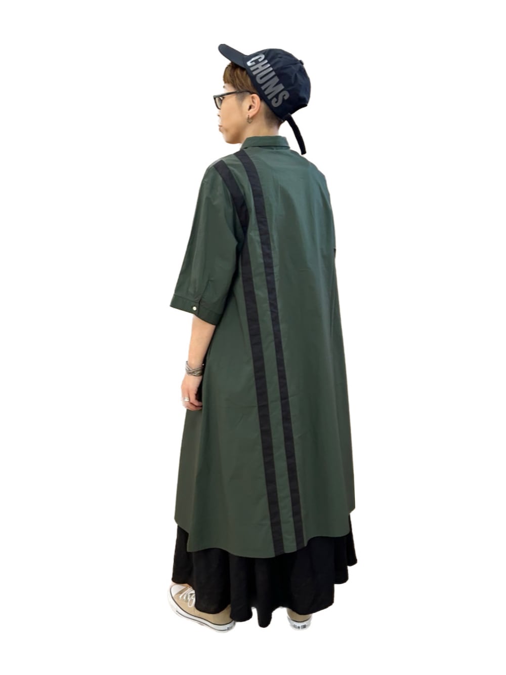 グリーン系のシャツワンピース、ブラック系のスカート、ベージュ系のスニーカーを着用したレディースの夏コーディネートの2枚目の写真