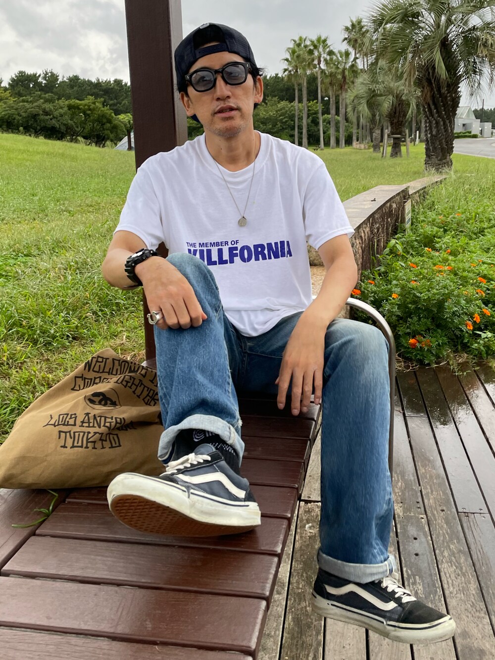 ホワイト系のTシャツ/カットソー、ブルー系のデニムパンツ、グリーン系のトートバッグを着用したメンズの冬コーディネートの4枚目の写真