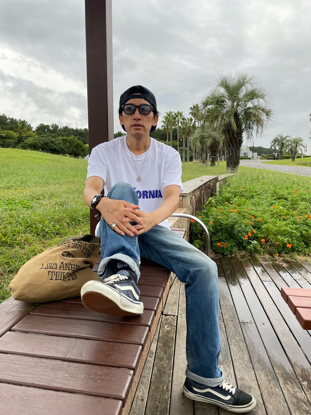ホワイト系のTシャツ/カットソー、ブルー系のデニムパンツ、グリーン系のトートバッグを着用したメンズの冬コーディネートの2枚目の写真