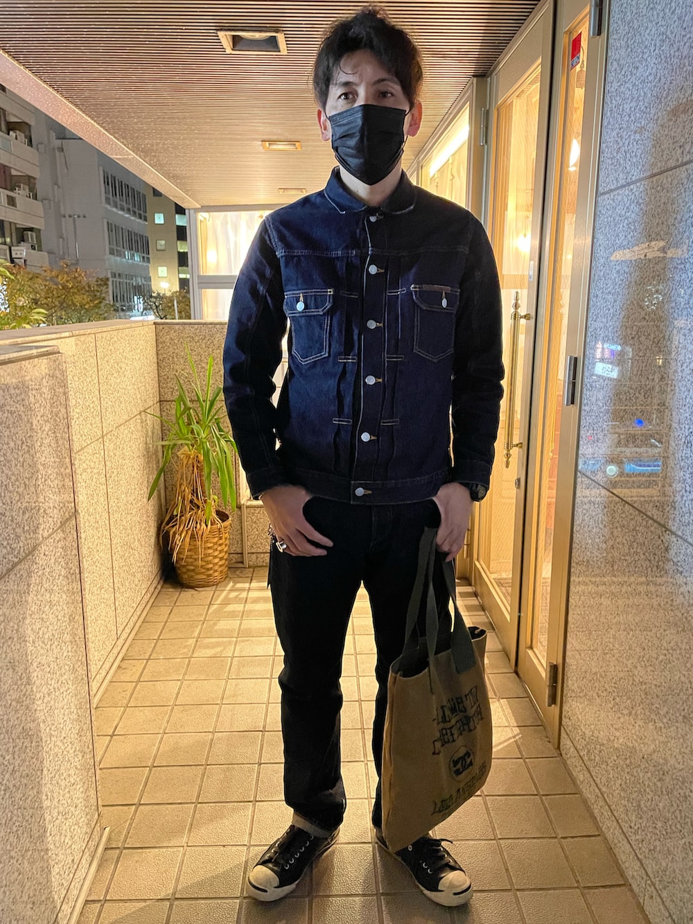 ブルー系のデニムジャケット、ブルー系のデニムパンツ、グリーン系のトートバッグを着用したメンズの冬コーディネートの3枚目の写真