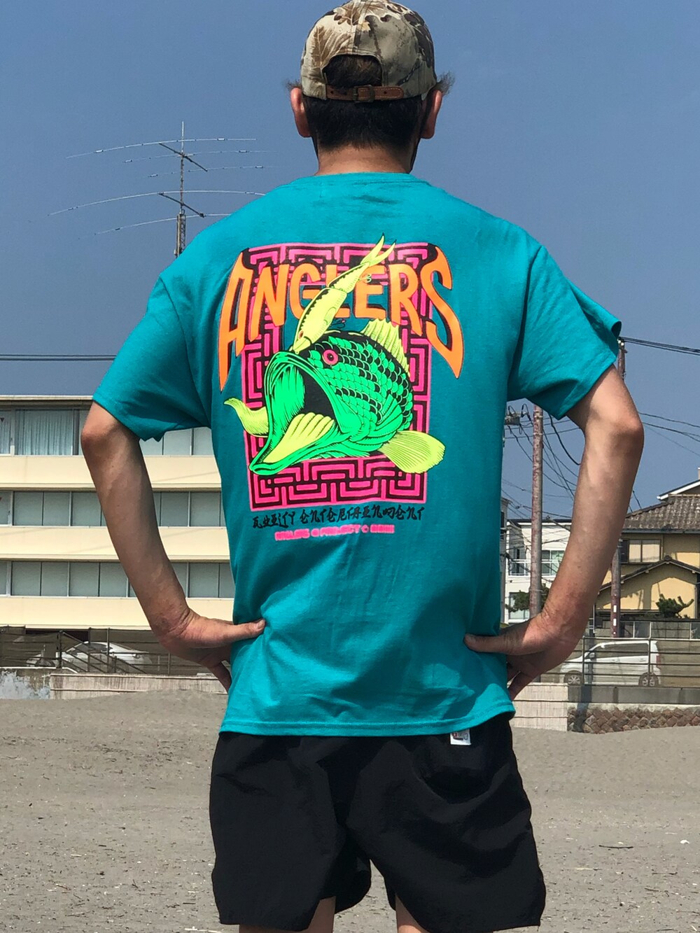 グリーン系のTシャツ/カットソー、ホワイト系のスニーカー、ブラック系の水着を着用したメンズの秋コーディネートの4枚目の写真