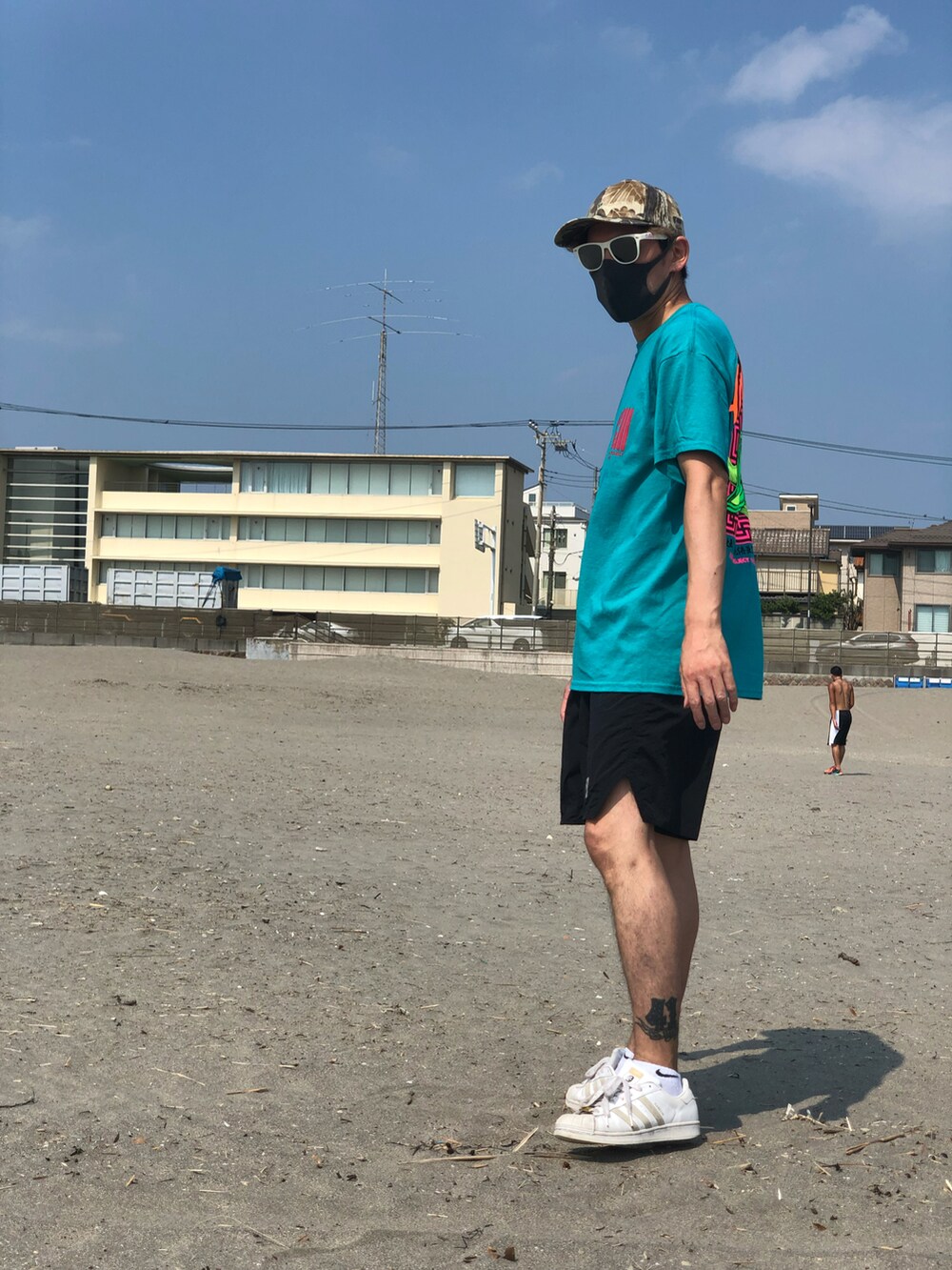 グリーン系のTシャツ/カットソー、ホワイト系のスニーカー、ブラック系の水着を着用したメンズの秋コーディネートの5枚目の写真