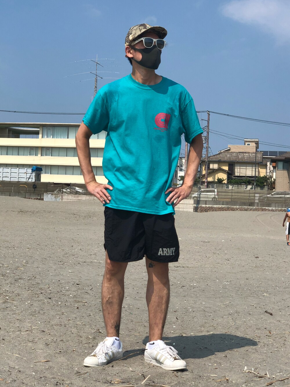 グリーン系のTシャツ/カットソー、ホワイト系のスニーカー、ブラック系の水着を着用したメンズの秋コーディネートの2枚目の写真