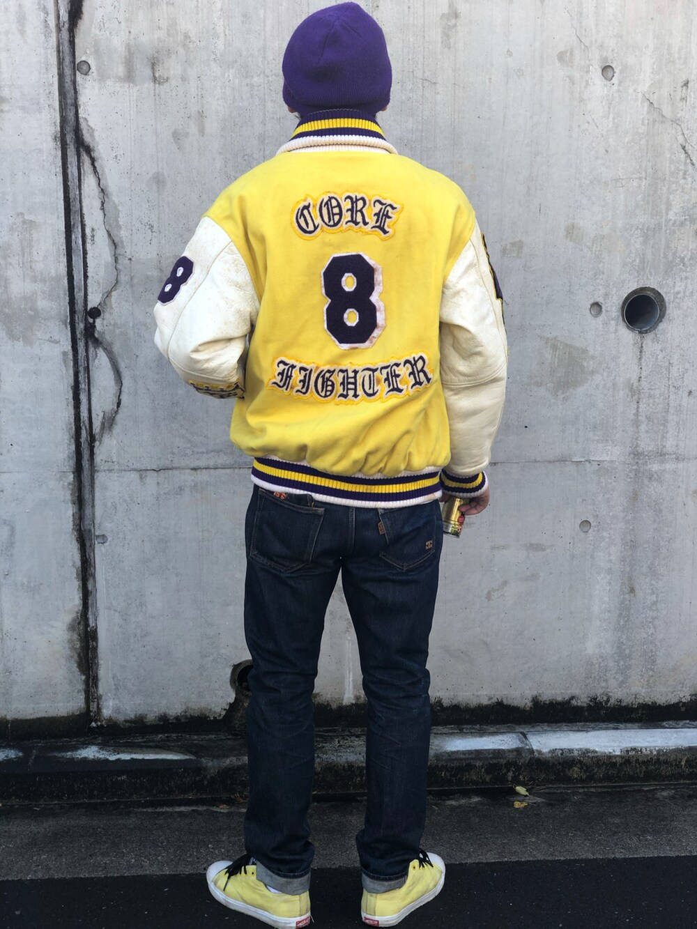 ホワイト系のTシャツ/カットソー、イエロー系のスタジャン、ブルー系のデニムパンツを着用したメンズの秋コーディネートの3枚目の写真