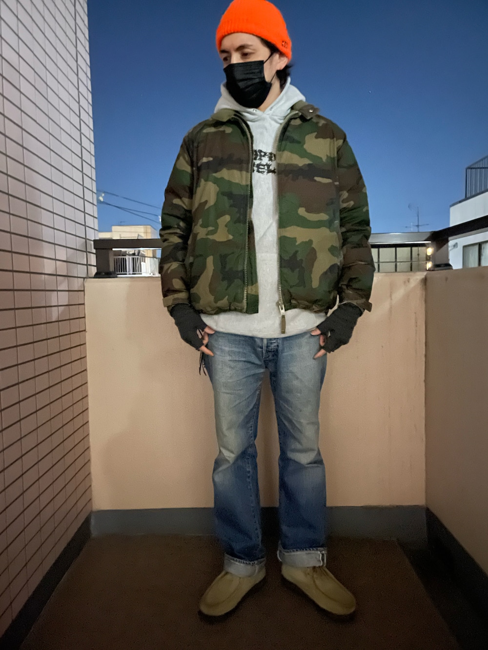 グレー系のパーカー、グリーン系のダウンジャケット/コート、ブルー系のデニムパンツを着用したメンズの冬コーディネートの2枚目の写真