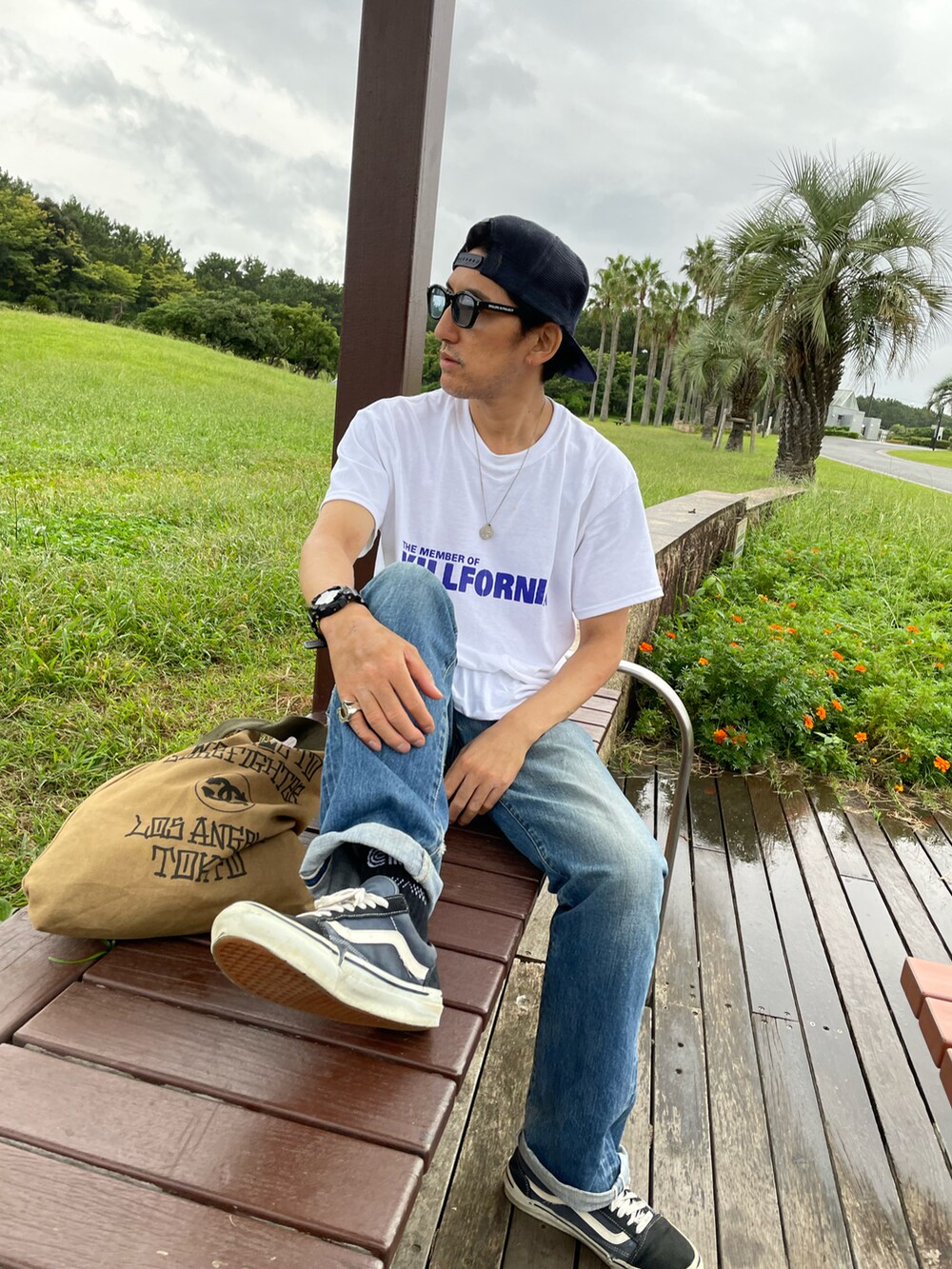 ホワイト系のTシャツ/カットソー、ブルー系のデニムパンツ、グリーン系のトートバッグを着用したメンズの冬コーディネートの3枚目の写真