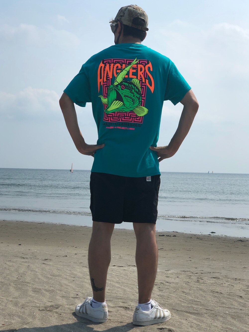 グリーン系のTシャツ/カットソー、ホワイト系のスニーカー、ブラック系の水着を着用したメンズの秋コーディネートの3枚目の写真
