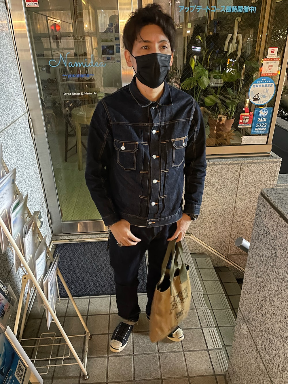 ブルー系のデニムジャケット、ブルー系のデニムパンツ、グリーン系のトートバッグを着用したメンズの冬コーディネートの2枚目の写真