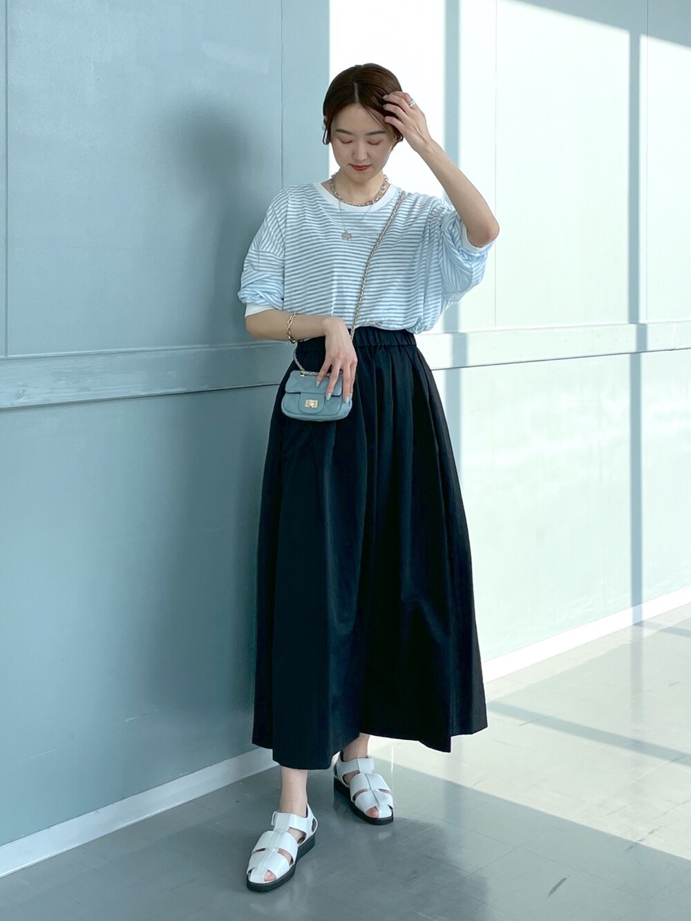 ブルー系のTシャツ/カットソー、ブルー系のショルダーバッグ、ブラック系のスカートを着用したレディースの春コーディネートの2枚目の写真