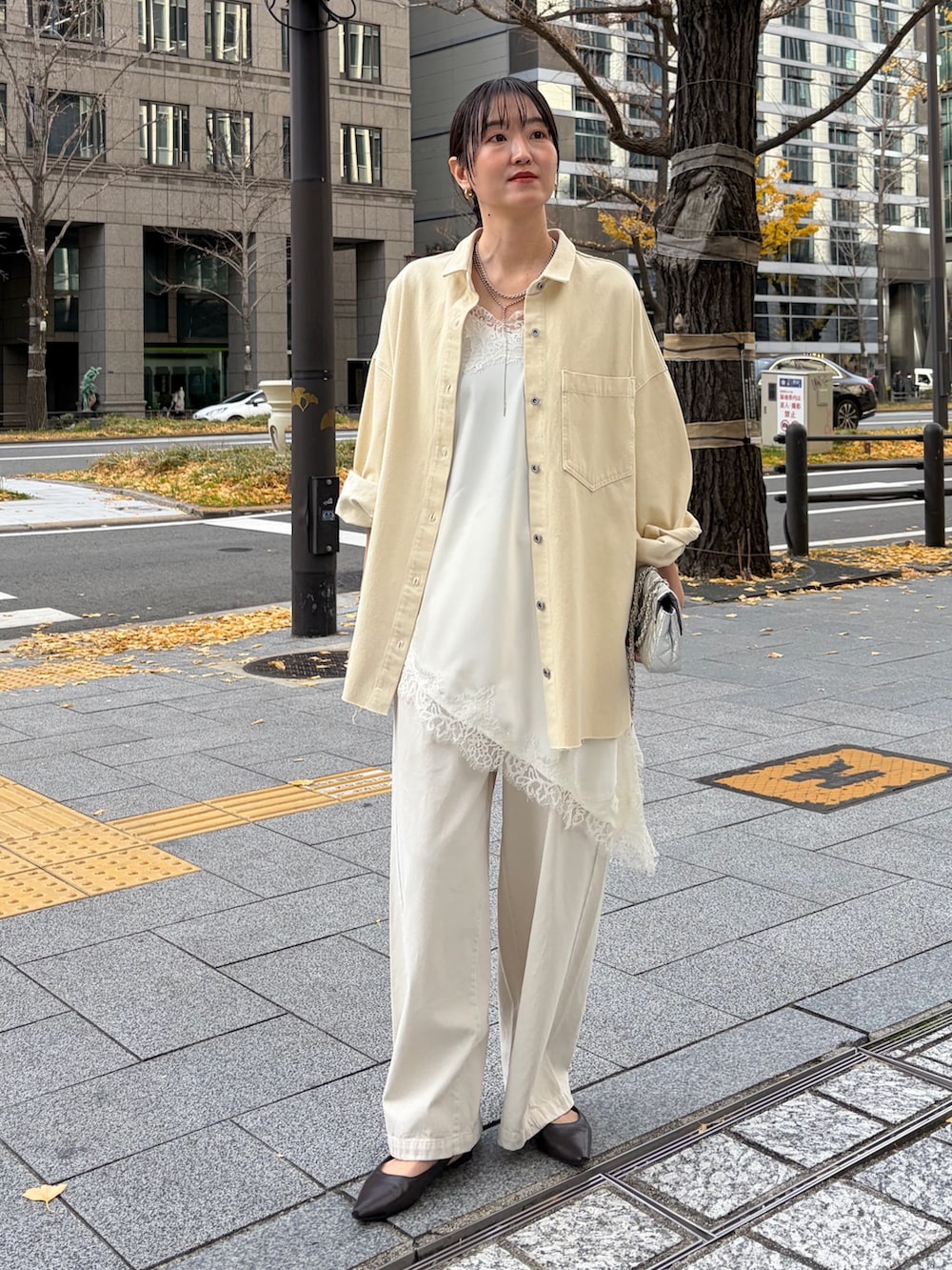 イエロー系のシャツ/ブラウス、ホワイト系のキャミソール、ベージュ系のデニムパンツを着用したレディースの冬コーディネートの3枚目の写真