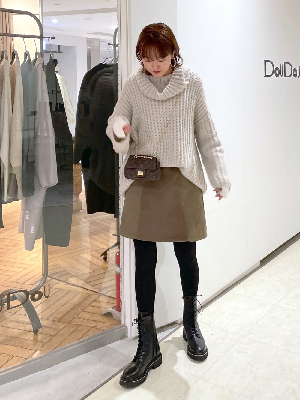 ベージュ系のニット/セーター、ブラウン系のショルダーバッグ、ベージュ系のスカートを着用したレディースの冬コーディネートの2枚目の写真