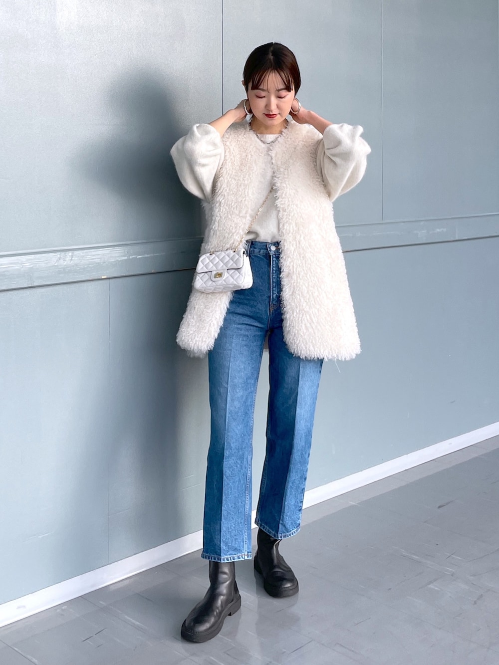 ホワイト系のベスト、ホワイト系のニット/セーター、ホワイト系のショルダーバッグを着用したレディースの冬コーディネートの2枚目の写真