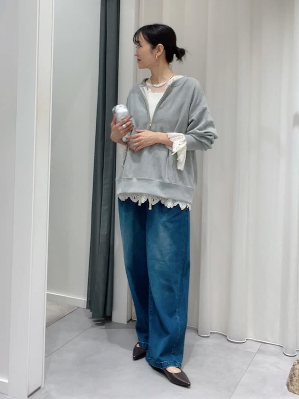 グレー系のスウェット、ホワイト系のシャツ/ブラウス、ブルー系のデニムパンツを着用したレディースの秋コーディネートの2枚目の写真