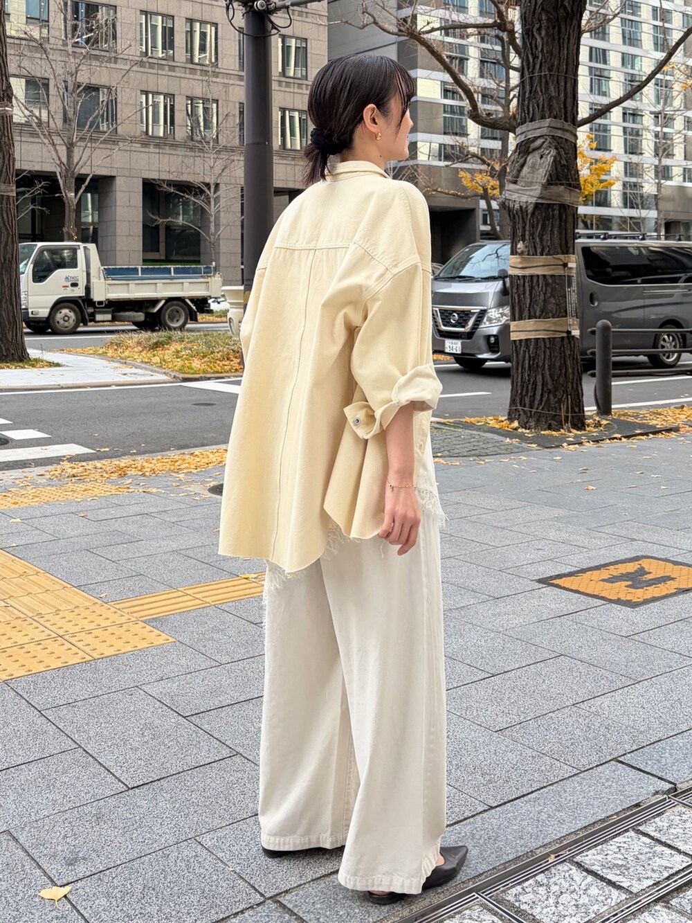 イエロー系のシャツ/ブラウス、ホワイト系のキャミソール、ベージュ系のデニムパンツを着用したレディースの冬コーディネートの2枚目の写真