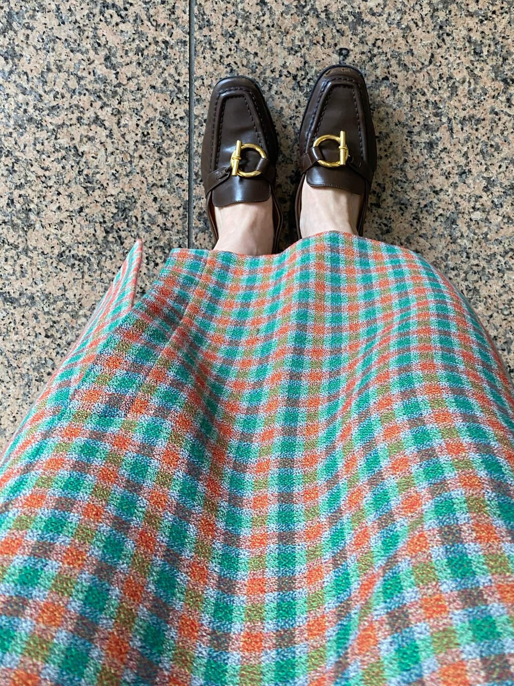 グリーン系のスカート、ホワイト系のTシャツ/カットソー、ブラウン系のローファーを着用したレディースの秋コーディネートの2枚目の写真