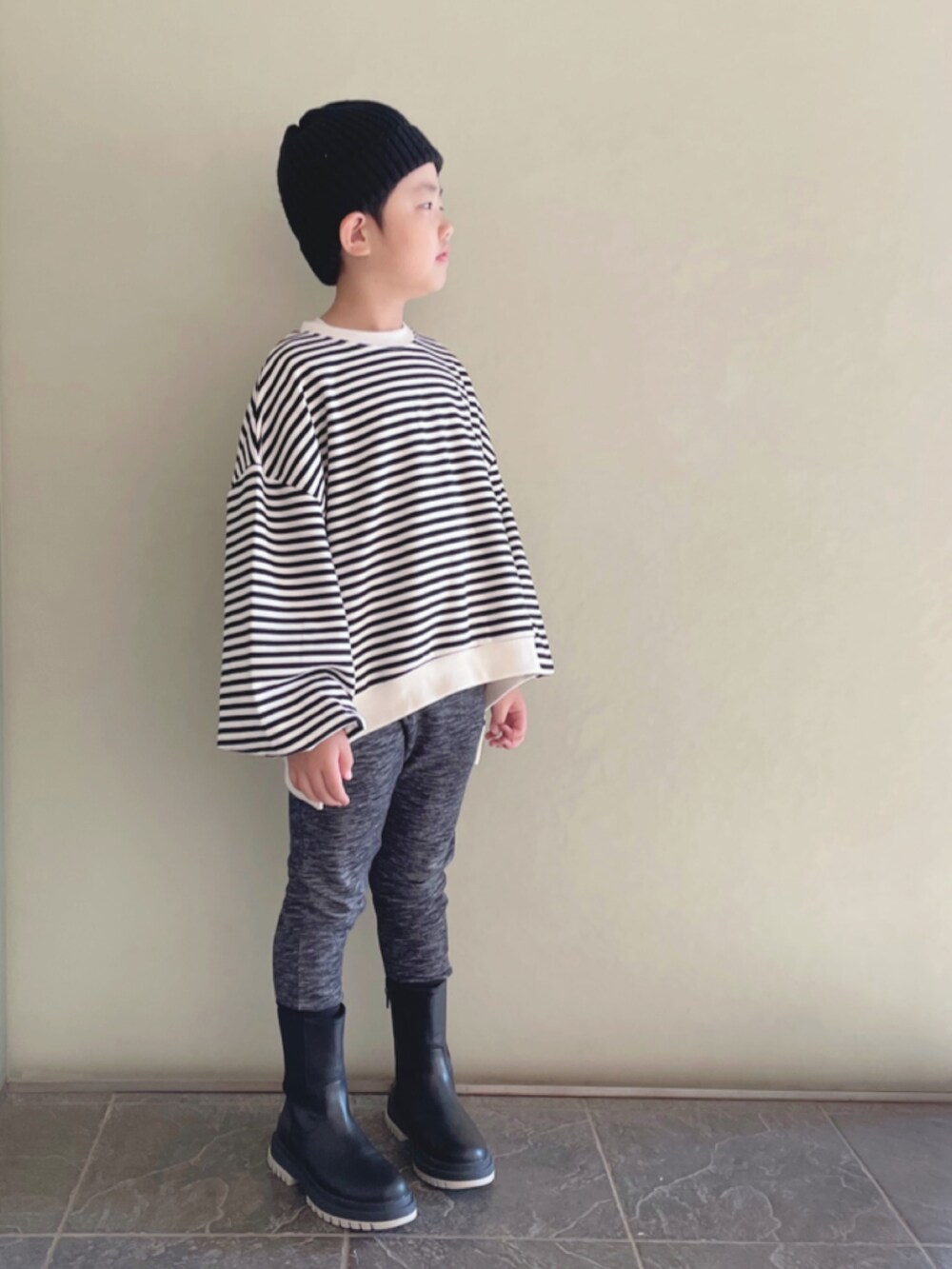 ブラック系のスウェットパンツ、ブラック系のブーツ、ベージュ系のTシャツ/カットソーを着用したキッズの冬コーディネートの2枚目の写真