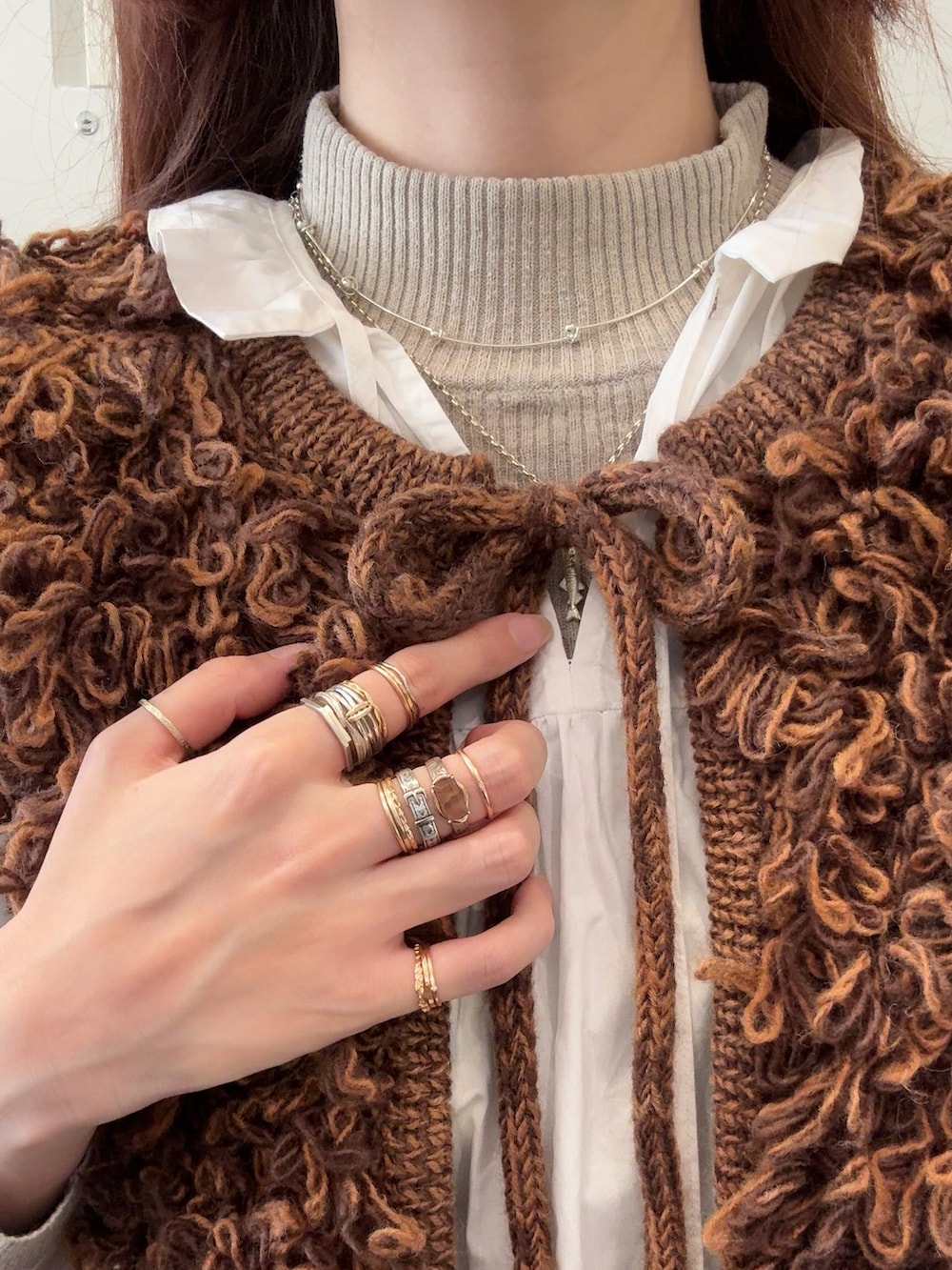 ブラウン系のベスト、シルバー系のネックレス、その他のチャームを着用したレディースの冬コーディネートの3枚目の写真