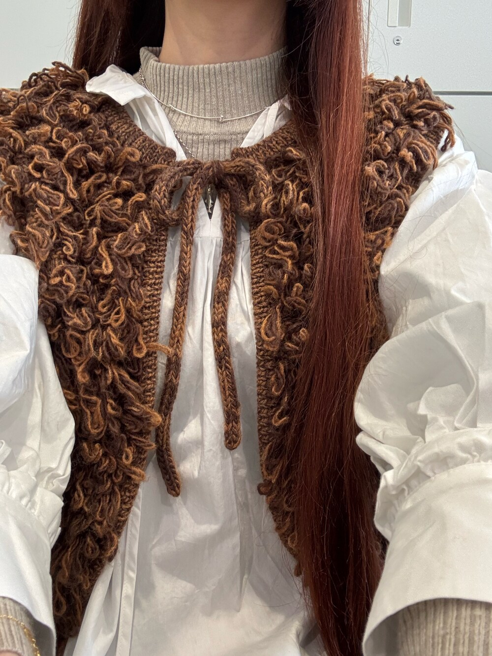 ブラウン系のベスト、シルバー系のネックレス、その他のチャームを着用したレディースの冬コーディネートの2枚目の写真